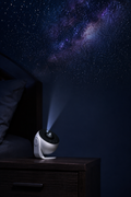 Stellara projector on a bedside table projecting the Milky Way